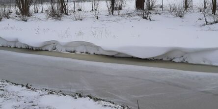 Aan de bevroren waterkant golf de sneeuw omhoog en omlaag